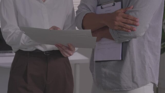  Client pointing at document during business contract signing meeting.Close up of hands reviewing financial insurance contract agreement details.