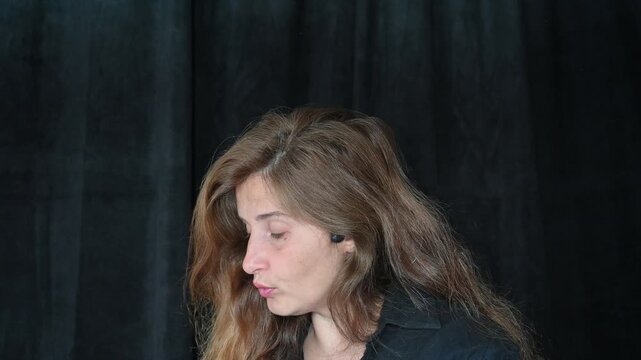 portrait of a woman on a black background
Woman with long hair reading and talking,