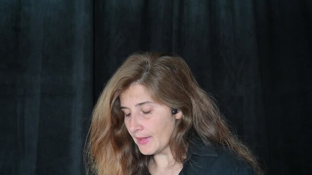 portrait of a woman on a black background
Woman with long hair reading and talking,