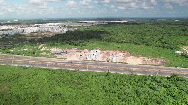 Aerial drone shot of a highway intersection adjacent to a residential construction project, capturing urban development, coastal topography, and regional infrastructure