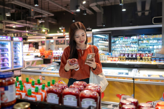 Woman comparing product labels and prices using smartphone