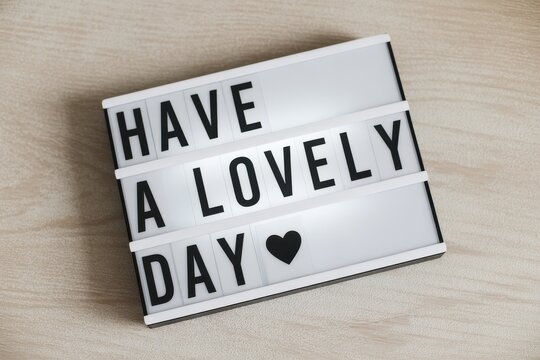 Have a Lovely Day text message on cinema light box with heart over wooden surface