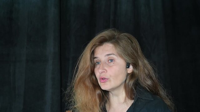 portrait of a woman on a black background
Woman with long hair reading and talking,
