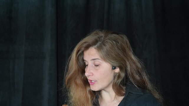 portrait of a woman on a black background
Woman with long hair reading and talking,