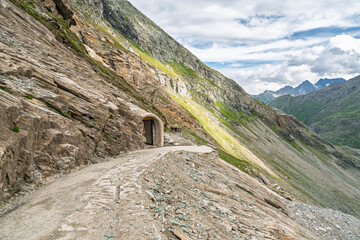 Fototapeta premium A scenic view of a mountain road with a tunnel in Solden, Austria, featuring the Alps landscape on a cloudy day. The rugged terrain and natural beauty of the Austrian Alps are.