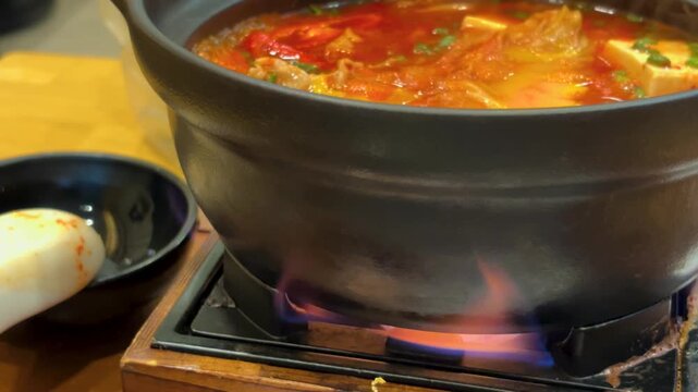 Static Close-Up of Spicy Asian Hot Pot Simmering over Open Flame Stove