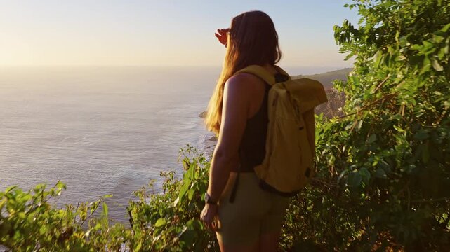 Young Female Tourist Photographing Ocean View From Uluwatu Cliff During Golden Sunset, Travel Memory, Mobile Technology And Exploration