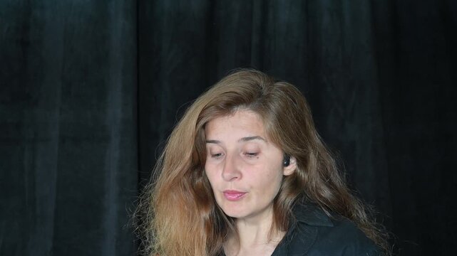 portrait of a woman on a black background
Woman with long hair reading and talking,