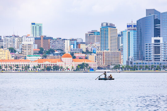 Luanda, Angola - May 20, 2026: Local fishermen in small wooden boat on foreground with modern city skyline skyscrapers and financial district building