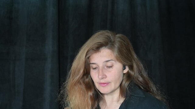 portrait of a woman on a black background
Woman with long hair reading and talking,