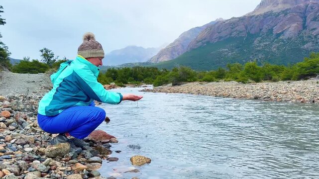 A female hiker dips her hands in the water of the Rio Blanco near El Chalten in Argentinian Patagonia
