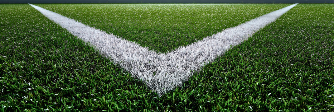 Close up view of freshly painted white penalty spot lines on a vibrant green grass field under bright lighting