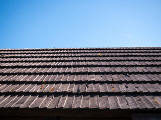 Naklejka premium Traditional wooden shingle roof under a clear blue sky, showcasing natural roofing materials, rustic architecture and durable construction with ample copy space.