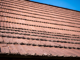 Fototapeta premium Aged wooden shingle roof with exposed and loosening nails, close-up of weathered roofing material highlighting maintenance, repair and building inspection needs.