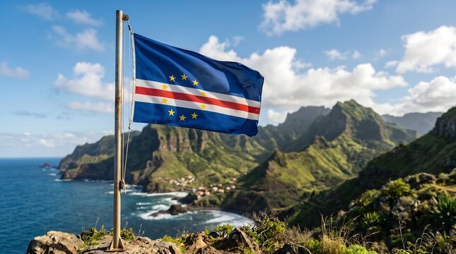 Cape Verde flag waving on flagpole against green mountain coastline and blue ocean under daylight