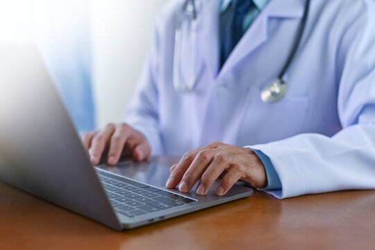 doctor is working on a computer in the office during a medical consultation.