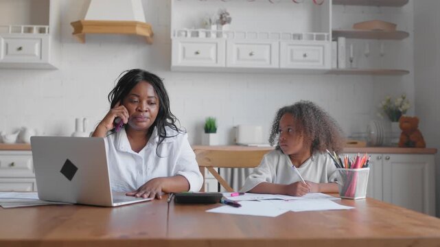 Housewife calling by mobile at home, portrait of woman and her child in kitchen. Motherhood and childhood, african american ethnicity, ordering goods by phone, call to delivery, little girl drawing