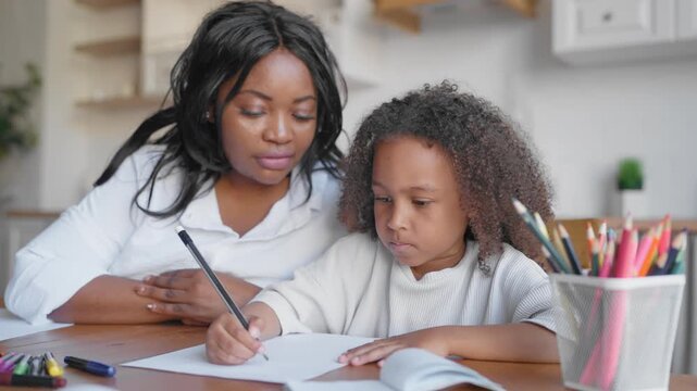 Teacher teaching smart little girl to write letters and words in notebook. Family time and parenting, african american mother and her preschooler daughter practicing spelling and english orthography