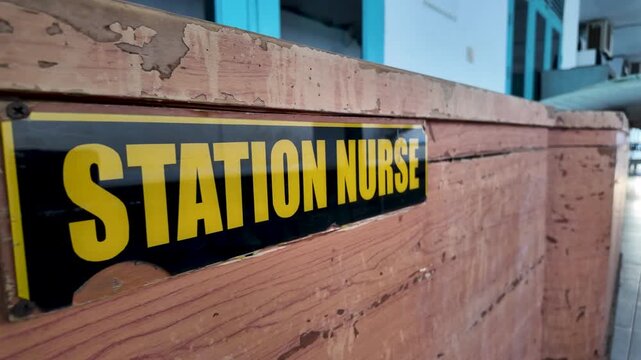 Station Nurse Sign on Weathered Wooden Desk in Quiet Hospital Corridor Nursing Station