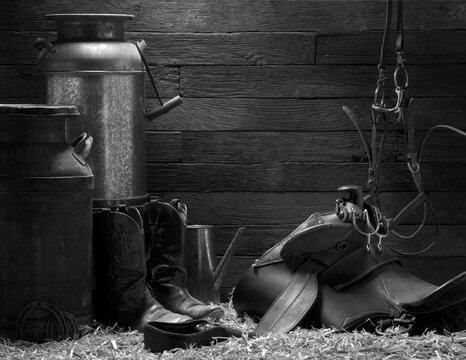 Western rustic background with cowboy boots, saddle, pitcher, horseshoes and spurs