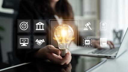 A person holds a glowing light bulb representing innovation, surrounded by digital icons...