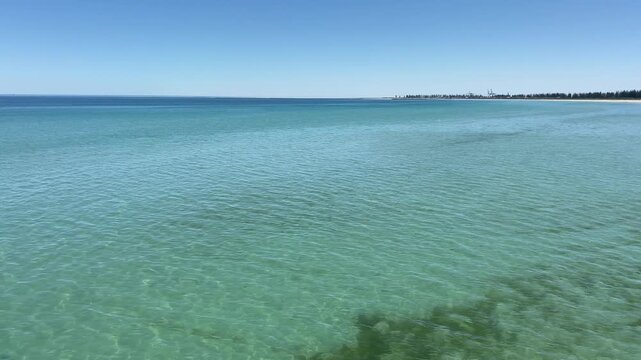 Calm turquoise sea water with gentle ripples reflecting the sunlight. Clear, pristine ocean surface meeting a cloudless blue sky at the horizon