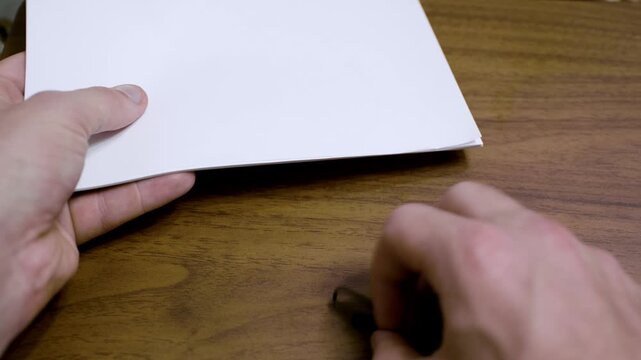 Close up of a hand using a paper clip connecting to a stack of paper. A4 size paper for printer stuck together with a paper fastener