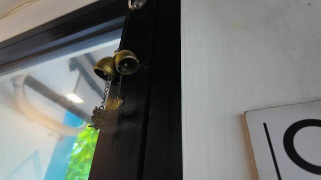 Traditional brass door bells swinging on a black frame