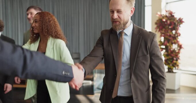 Businesspeople partners greeting with handshake at meeting. The team of colleagues and executives meets in a modern office, showing agreement. Symbolizes partnership, trust, success in business.