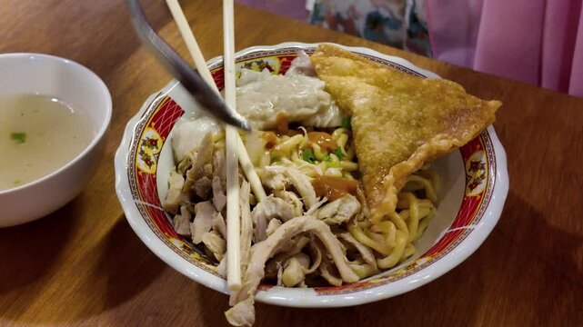 Pouring Savory Broth Soup into a Bowl of Indonesian Mie Ayam