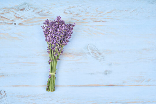 Top view of a fragrant lavender bouquet on a pastel blue wooden board. Rustic floral flat lay with natural purple flowers, copy space and soft vintage style.