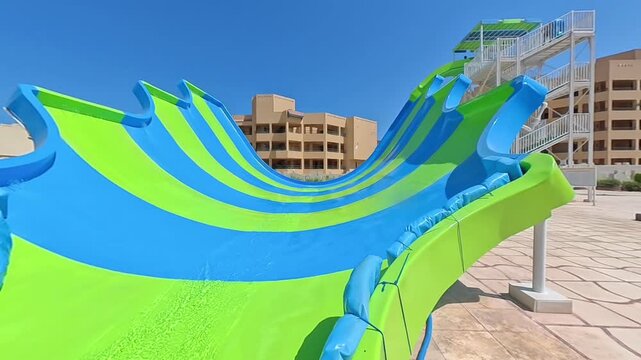 Clear water flowing down a large colorful waterslide at an aquapark on a sunny summer day