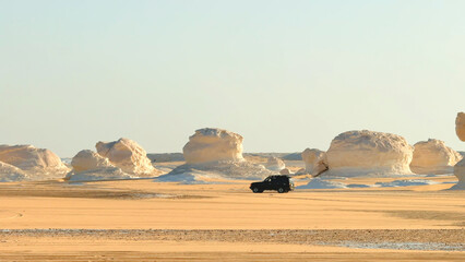 4x4 jeep driving fast across sandy desert plain among rock formations © Bankerok