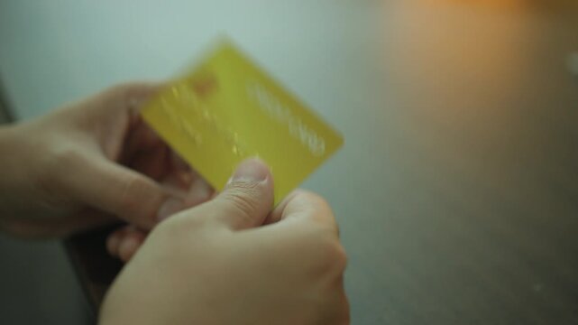 Closeup of Customer Hands Holding Golden Credit Card and flip card, Verifying Financial Credentials for Online Shopping. business idea concept.