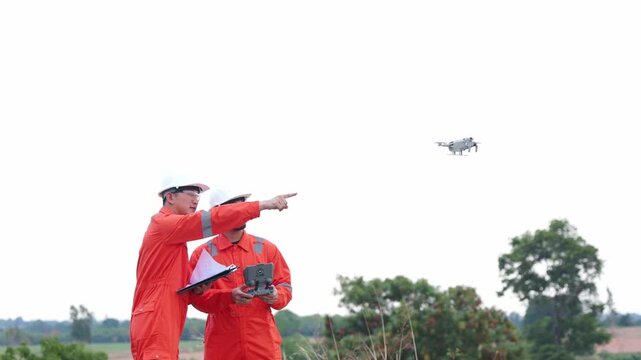 Aged Asian safety workers operating modern drone technology inside turbine power farm location. Two male industrial engineers conducting high tech utility systems inspection.
