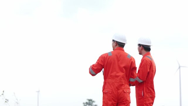 Aged Asian helmet technicians collaborating on windmill green power maintenance grid network. Two industrial engineering experts working inside sustainable alternative utility.