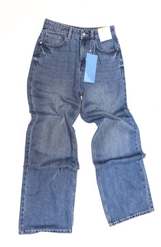 Blue straight leg baggy women's jeans with blank paper tags on white background