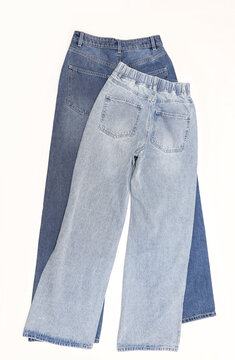 Two pair of blue straight leg baggy women's jeans on white background