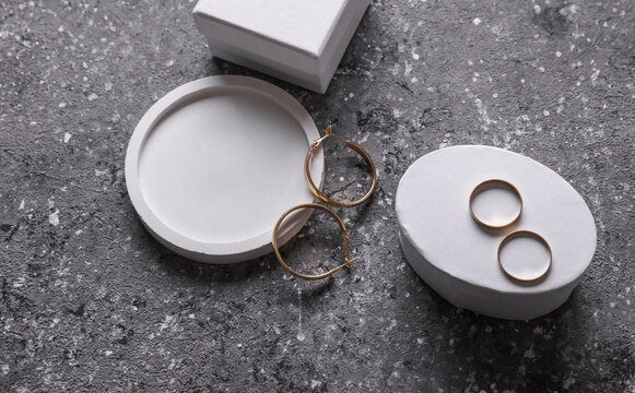 Gold earrings and rings in tray with jewelry box on concrete background