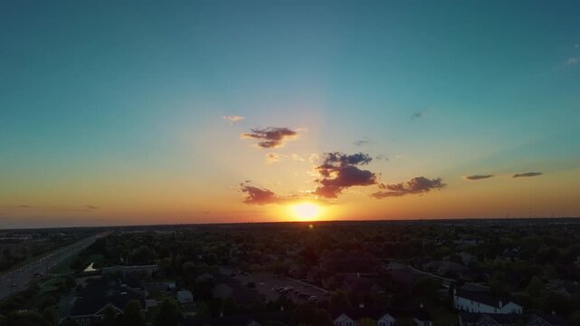 Beautiful blue and orange sunset with clouds glowing above distant landscape during golden hour evening sky