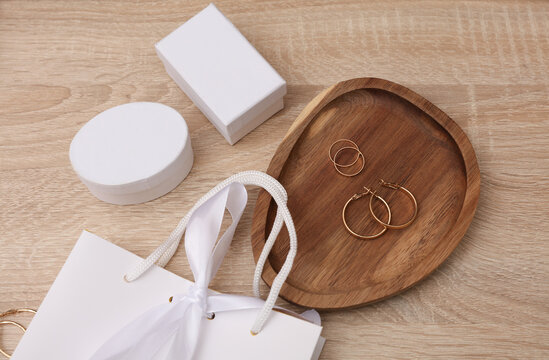 Gold earrings and rings in a tray with white boxes on the table