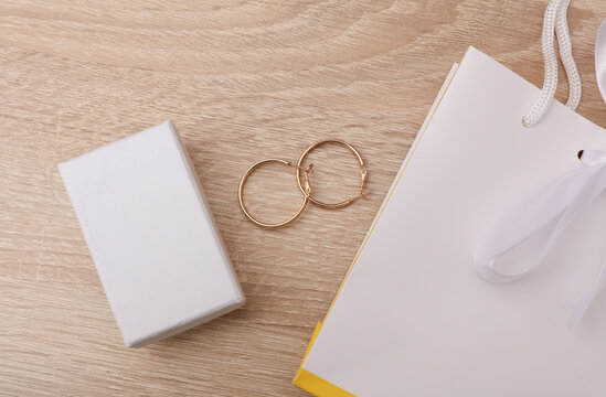 White jewelry bag and box and gold earrings on the table. Mockup for design