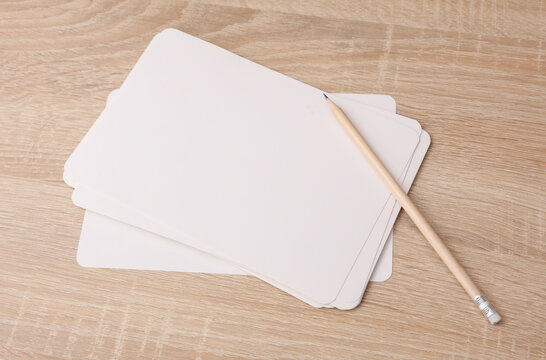 White blank cardboard cards and a pencil on the table. Mockup for design