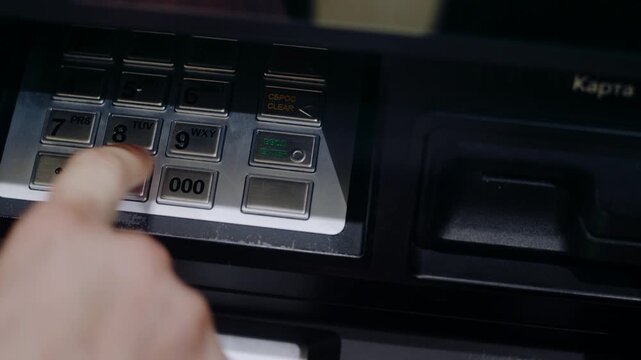 Close-up of a hand inserting a bank card into an atm and entering a secret personal code on the keypad