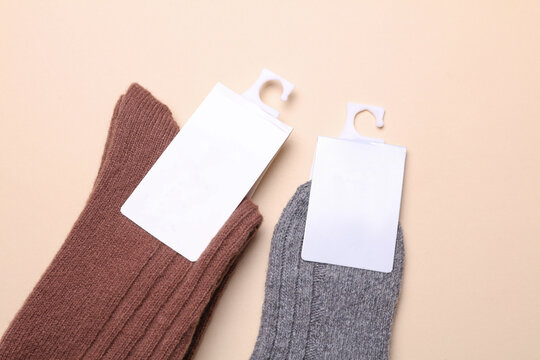 Woolen socks with a white blank tag on a beige background