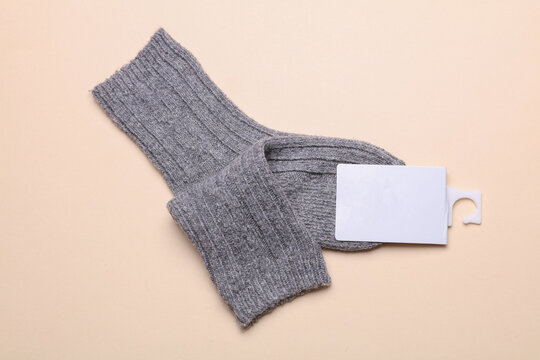 Woolen socks with a white blank tag on a beige background