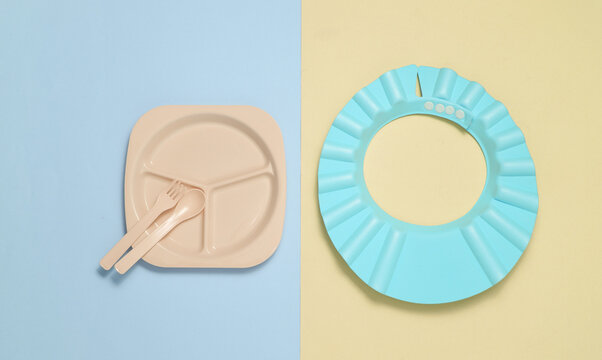 Set of plastic dishes for feeding baby on pastel background. Top view