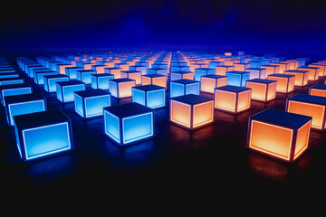 Fototapeta premium A grid of glowing blue and orange cubic light installations arranged in a dark, futuristic space, creating a striking visual contrast.