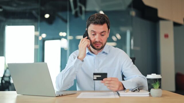 Close-up of worried businessman or IT specialist making phone call to support about declined credit card. Annoyed corporate worker, manager or freelance designer solving banking problem at office.