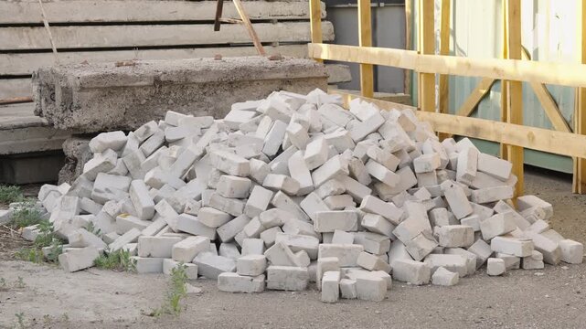 A large messy pile of white bricks on the ground at a construction site.